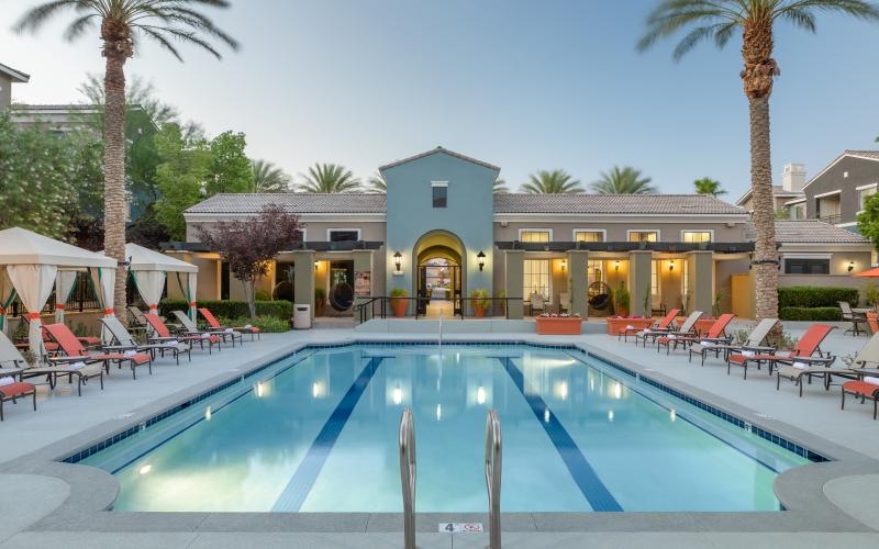 a swimming pool with chairs and umbrellas next to a house