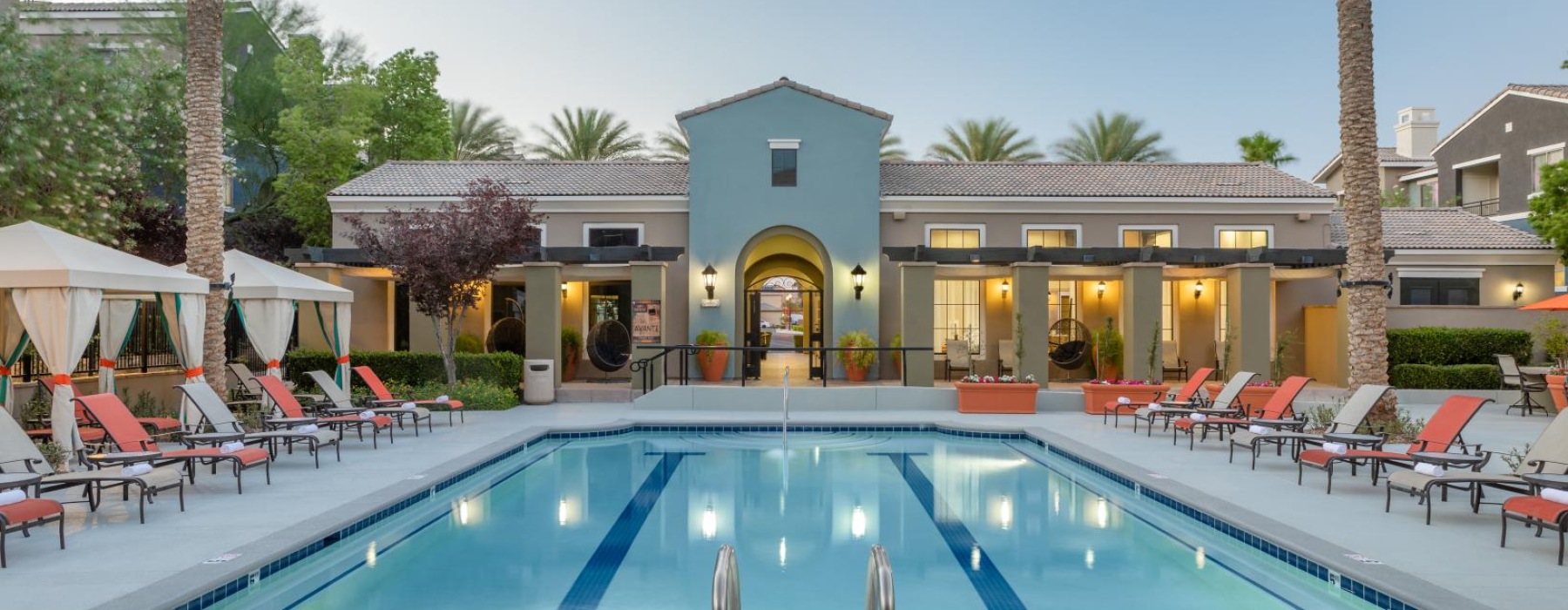 a swimming pool with chairs and umbrellas next to a house