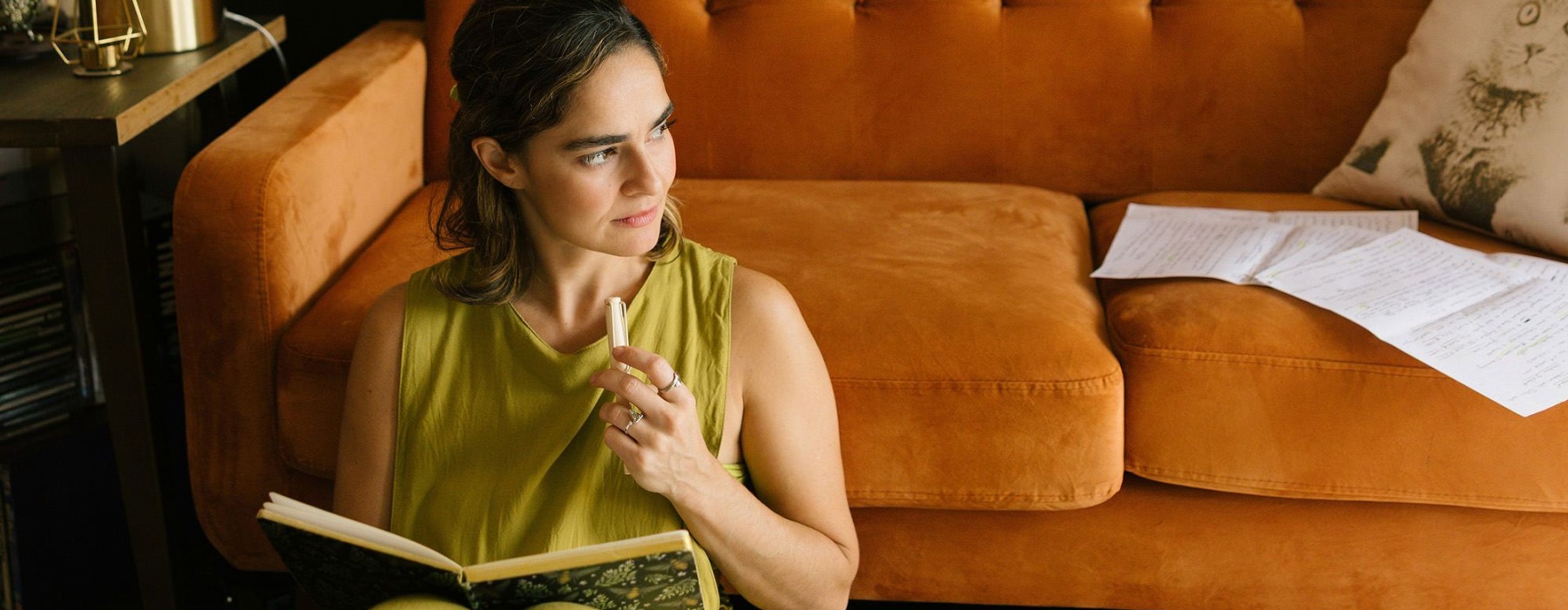 woman sitting on the floor by a couch reading a book