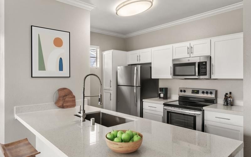 a kitchen with white cabinets and a bowl of fruit on a counter